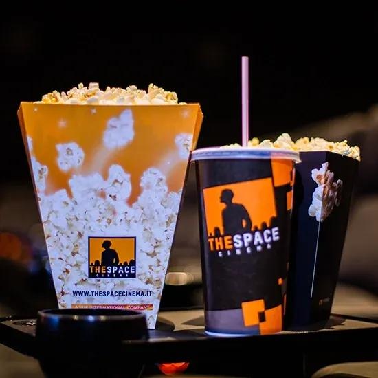 Biglietti The Space con menu a 11,99 €: film, pop corn e bibita inclusi 2 Pop corn e bibita del menu The Space Cinema appoggiati sulla poltrona in sala